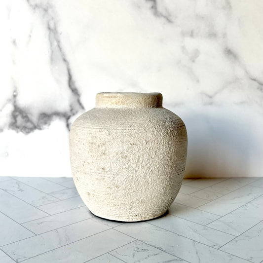 A small light gray vase on a gray surface